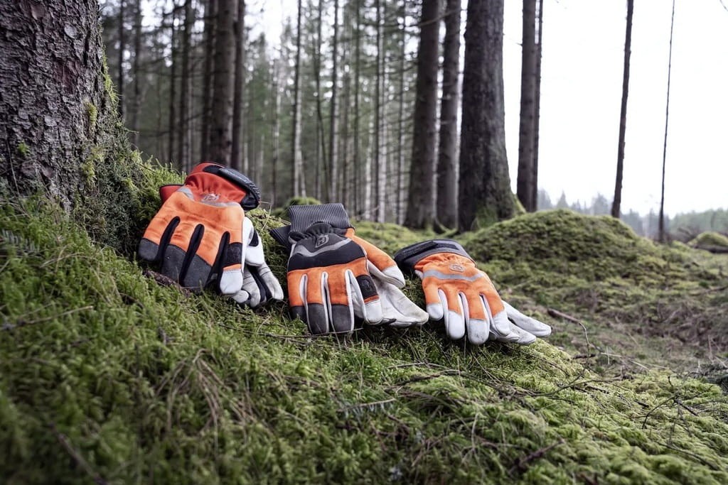 Rękawice Husqvarna leżące w lesie na mchu - zastosowanie leśne