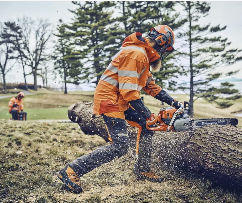 Profesjonalny drwal pracujący pilarką Husqvarna 562 XP przy ścince dużego drzewa