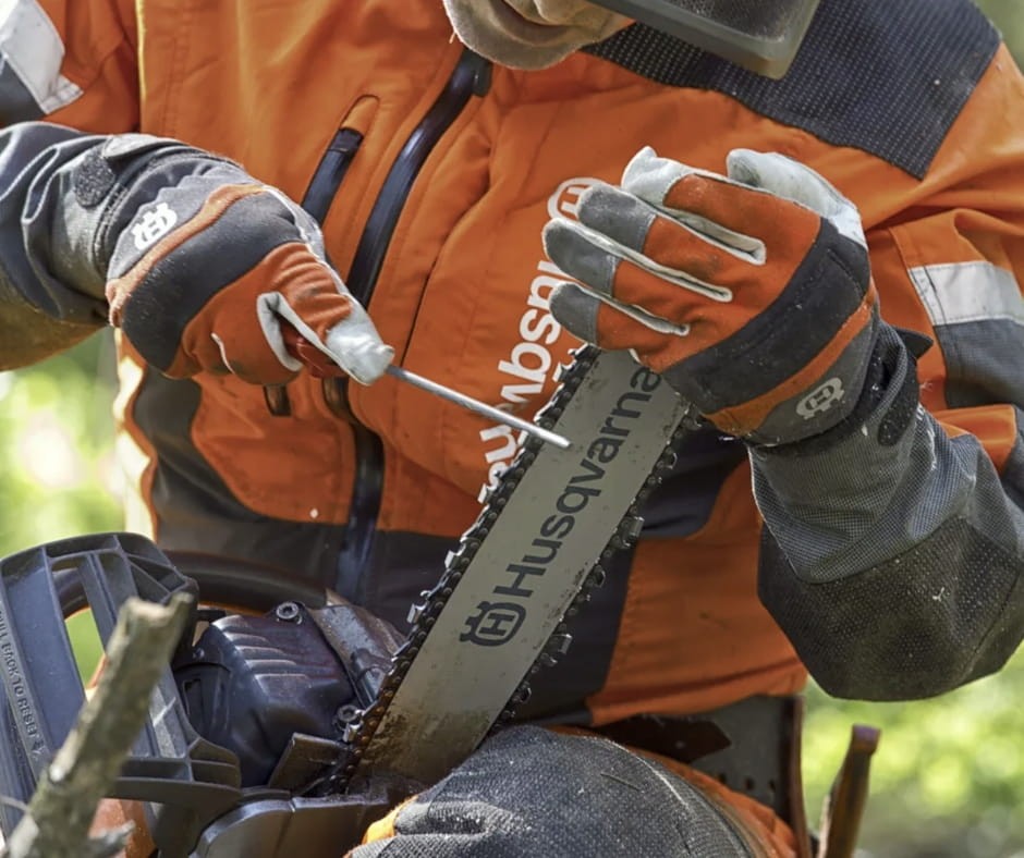 Pilarz w lesie używający łańcucha Husqvarna X-Cut do ścinki drzewa