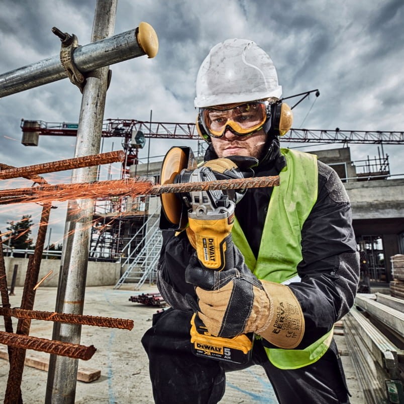Praca na wysokości - cięcie metalu bezpieczną szlifierką DeWalt z włącznikiem łopatkowym