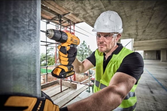 Pracownik budowlany wiercący w metalowym profilu wkrętarką DeWalt DCD776