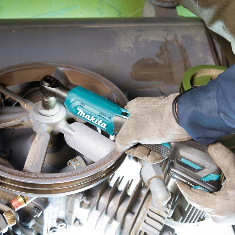 Mechanik używający grzechotki Makita WR100 w ciasnej komorze silnika