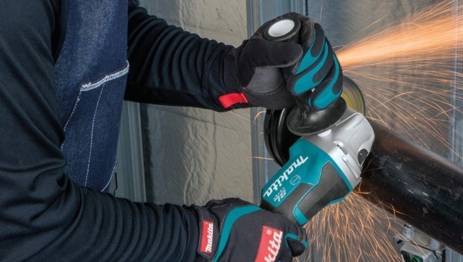 Operator używający szlifierki Makita DGA517Z do szlifowania powierzchni stalowej