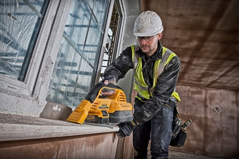 Pracownik budowlany odkurzający parapet po montażu odkurzaczem DeWalt DCV517