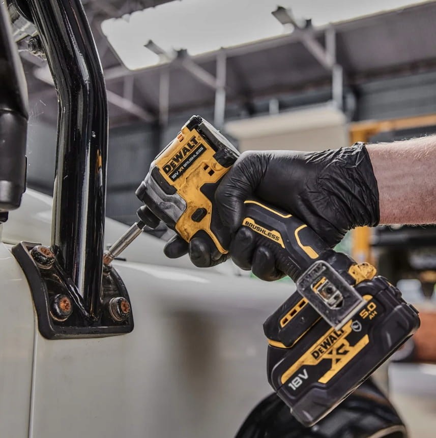 Mechanik w rękawicach używający małej zakrętarki DeWalt DCF850 w ciasnym miejscu