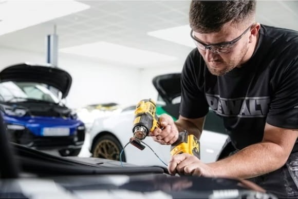 Zastosowanie w motoryzacji - mechanik używający opalarki DeWalt przy karoserii
