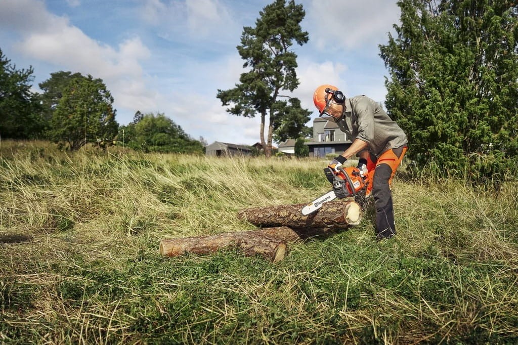 Prace porządkowe w terenie - użytkownik z pilarką Husqvarna 445 II